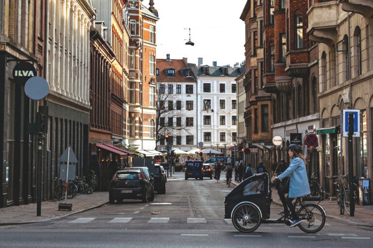 Gadeudsigt på Vesterbro i København med cyklister, fodgængere og biler - centralt område med ferielejligheder