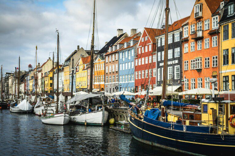 Charmerende Nyhavn med farverige huse og turister, et populært spisested tæt på ferieboliger i København